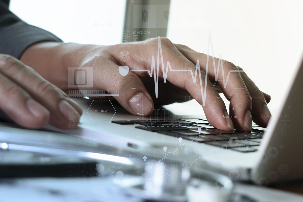 close up of Medicine doctor hand working with modern computer and medical diagram layers on wooden desk as medical concept